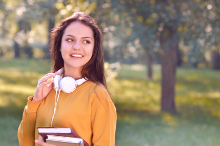 Young beautiful and trendy student girl hold books and look aside. Casual teenage girl preparing to school. Youth and carefree conceptの写真素材