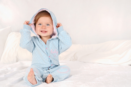 Portrait of a little smiling girl dressed in blue pajamas at home. Happy childhood conceptの写真素材
