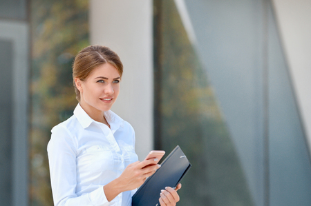 Portrait of cheerful young woman using smartphone outdoors. Business conceptの写真素材