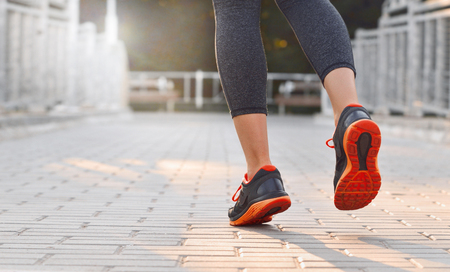 Low angle rear portrait of female runner in action on the bridgeの写真素材