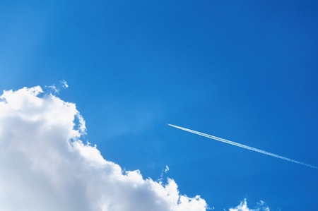 Blue sky background with a plane track. Jet of airplane in the blue skyの写真素材