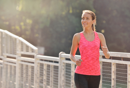 Woman running on bridge. Woman runner jogging on urban road training for marathon. Fit girl fitness athlete model exercising outdoorの写真素材