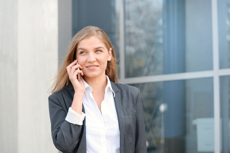 Successful businesswoman or entrepreneur talking on cellphone while walking outdoorの写真素材
