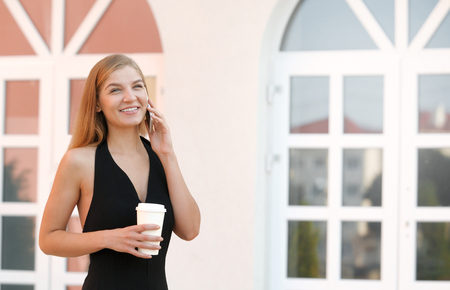 Portrait of cheerful businesswoman enjoying coffee break outdoors on sunny dayの写真素材