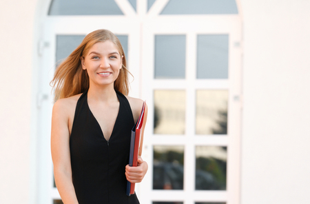 Happy young business woman with a folder at the office buildingの写真素材