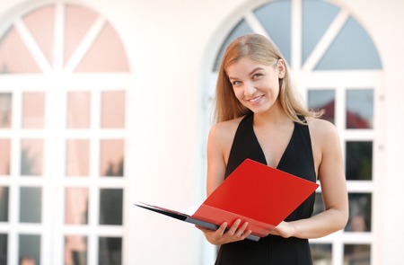 Happy young business woman with a folder at the office buildingの写真素材