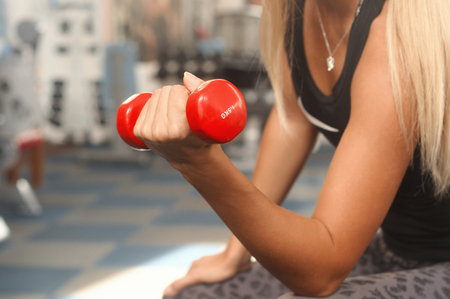 Sporty woman workout with dumbbell in gym. Healthy lifestyle and exercising. Side viewの写真素材