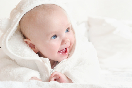 Adorable happy cute little girl with wide smile wearing a white bathrobe. Happy childhood conceptの写真素材