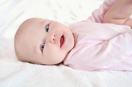Portrait of a cute newborn baby lying on white bed sheet. Close up. Happy parenthood conceptの写真素材