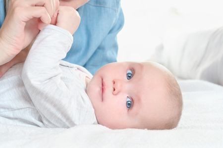 Mother play with her daughter on white bed background. Happy childhood and maternity concept.の写真素材