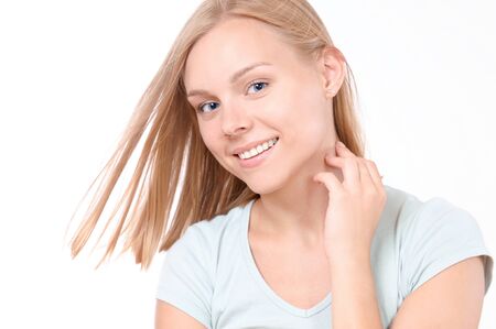Blonde female looking at camera and smiling. Studio shot of good-looking beautiful woman isolated against blank studio wallの写真素材
