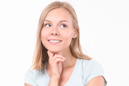 Pretty smiling joyfully female with blonde hair. Studio shot of good-looking beautiful woman isolated against blank studio wallの写真素材