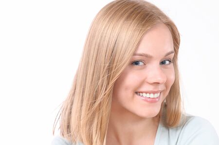 Pretty smiling joyfully female with blonde hair. Studio shot of good-looking beautiful woman isolated against blank studio wallの写真素材