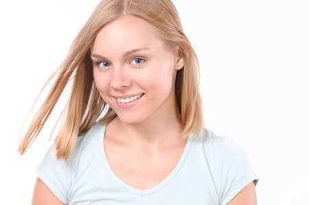 Pretty smiling joyfully female with blonde hair. Studio shot of good-looking beautiful woman isolated against blank studio wallの写真素材