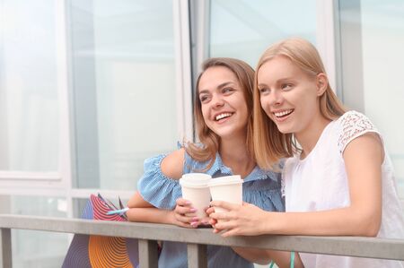 Attractive young women with take away coffee in summer city. Lifestyle, friendship and people conceptの写真素材