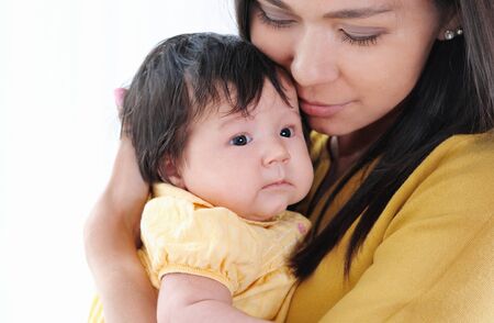 Pretty young woman holding a newborn baby in her arms. Portrait of mother and little baby. Happy family concept.の写真素材