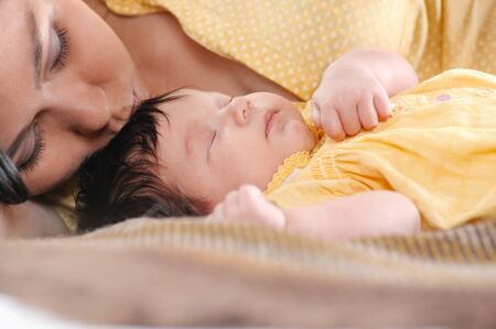 Pretty young woman holding a newborn baby in her arms. Portrait of mother and little baby. Happy family concept.の写真素材