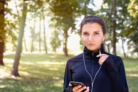 Portrait of young sporty woman running with headphones in the park outdoor. Healthy lifestyle conceptの写真素材