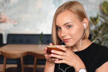 Young blonde woman having a cup of coffee in cafe.. Happy lifestyle concept.の写真素材