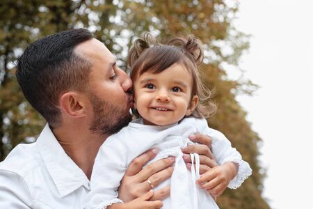 Father kissing her cute little baby girl in the park. Happy family conceptの写真素材