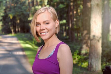 Portrait of young smilling sporty woman running in the fores outdoor early in the morning. Healthy lifestyle conceptの写真素材