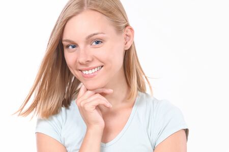 Pretty smiling joyfully female with blonde hair. Studio shot of good-looking beautiful woman isolated against blank studio wallの写真素材