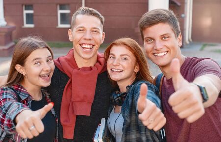 Happy smiling group of students giving thumbs up near university on background. Education conceptの写真素材