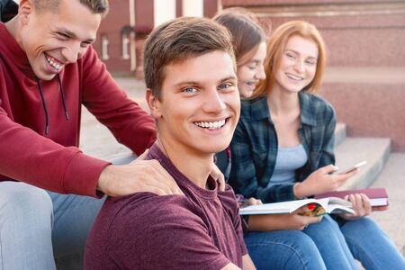 Two teenage boys having fun while studing against girls near university. Education conceptの写真素材