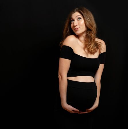 Studio shoot of happy emotional pregnant woman on black backgroundd. Motherhood conceptの写真素材