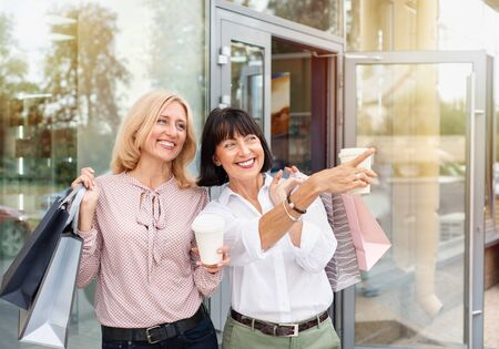 Two mature women having fun while doing shopping and drinking coffee. Pastime concept of mature peopleの写真素材