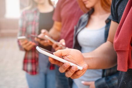 Close up shot of teenager group of people using their phones outdoors. Education, technology and happiness conceptの写真素材