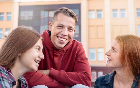 Portrait of happy smiling teenage boy chatting with girls while studying outdoors near university. Education conceptの写真素材