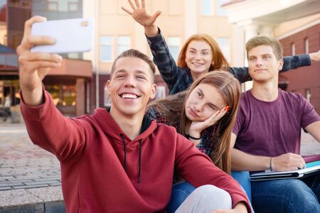 Happy smiling group of students taking picture on the phone outdoors near university. Education conceptの写真素材