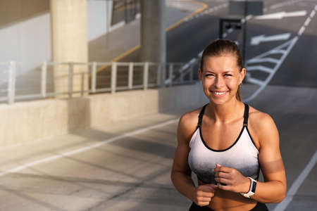 Happy fitness sporty woman running early in the morning city at sunrise. Healthy lifestyle concept.の写真素材