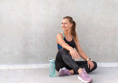Fitness sporty woman is having a break after running early in the morning city at sunrise. Healthy lifestyle concept.の写真素材