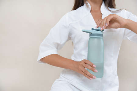 Close up photo of woman's hands with bottle of water in a white robe. Healthy eating concept.の写真素材