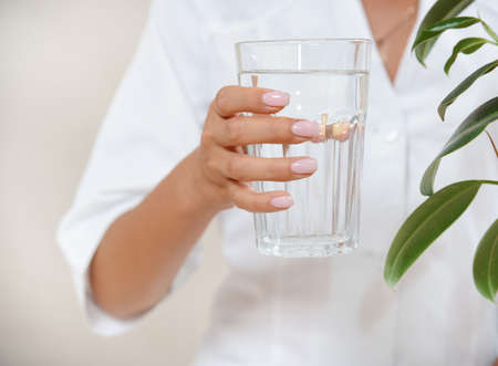 Close up photo of woman's hand with glass of water in a white robe. Healthy eating concept.の写真素材