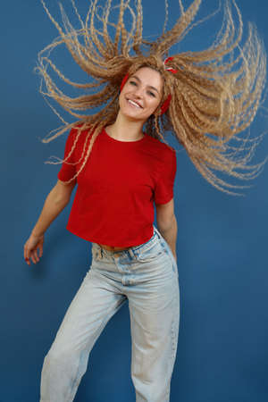 Young happy beautiful woman with blond curly hair dancing on blue background. Happy lifestyle...