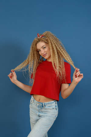 Young happy beautiful woman with blond curly hair dancing on blue background. Happy lifestyle concept.の写真素材
