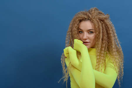 Portrait of young beautiful woman with blond curly hair on blue background. Happy lifestyle concept.の写真素材