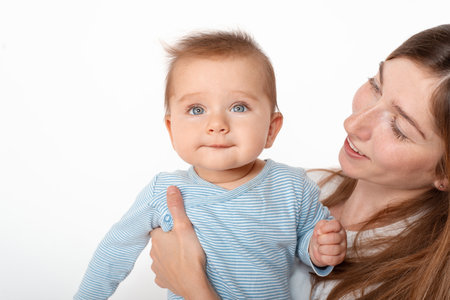 Mother holding cute happy baby boy with beautiful blue eyes on white background. Happy childhood and motherhood concept.の写真素材