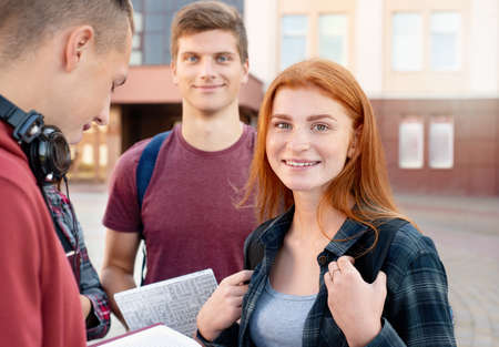Portrait of happy smiling teenager girl with freckles with group of students on background. Education conceptの写真素材