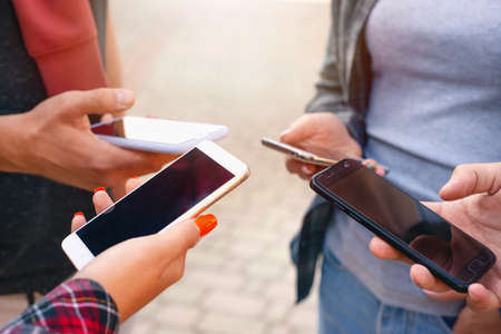 Close up shot of teenager group of people using their phones outdoors. Education, technology and...