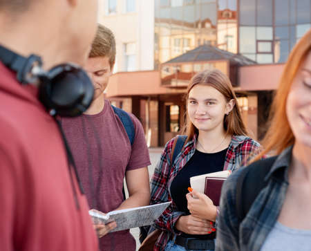 Happy teenager girl with books meets her friends near university. Education conceptの写真素材