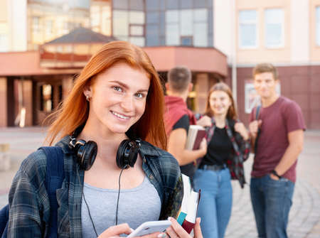Portrait of happy smiling teenager girl with freckles with group of students on background. Education conceptの写真素材