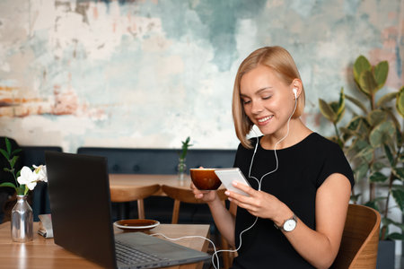 Modern business woman working on smart phone and laptop computer at coffee shop interior, internet distance work. Freelance working conceptの写真素材