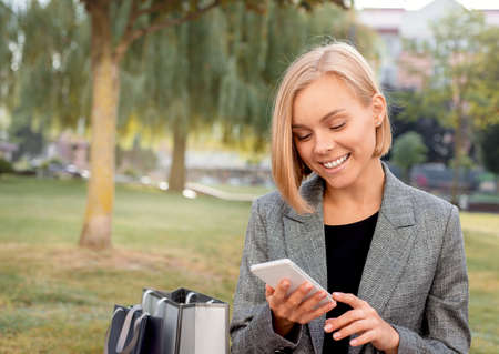 Beautiful woman in town with shopping bags looking at the phone. Happy lifestyle conceptの写真素材