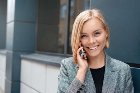 Portrait of a beautiful blonde business woman on the phone at the business center outdoors. Working lifestyle conceptの写真素材