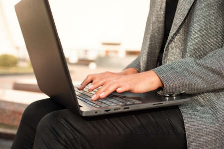 Closeup of woman hand typing on laptop keyboard. Working outdoors.の写真素材