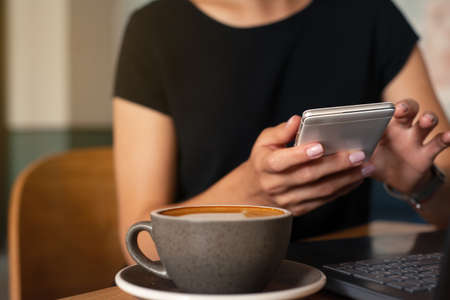 Closeup shoot of smart phone and laptop computer at coffee shop interior, internet distance work. Freelance working conceptの写真素材
